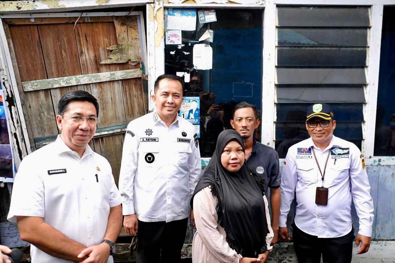 Pj Gubernur Agus Fatoni berdiri di depan rumah yang akan dibedah. (FOTO: Humas Pemprov Sumsel)